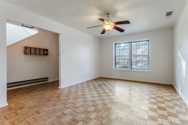 an empty room with windows and chandelier fan
