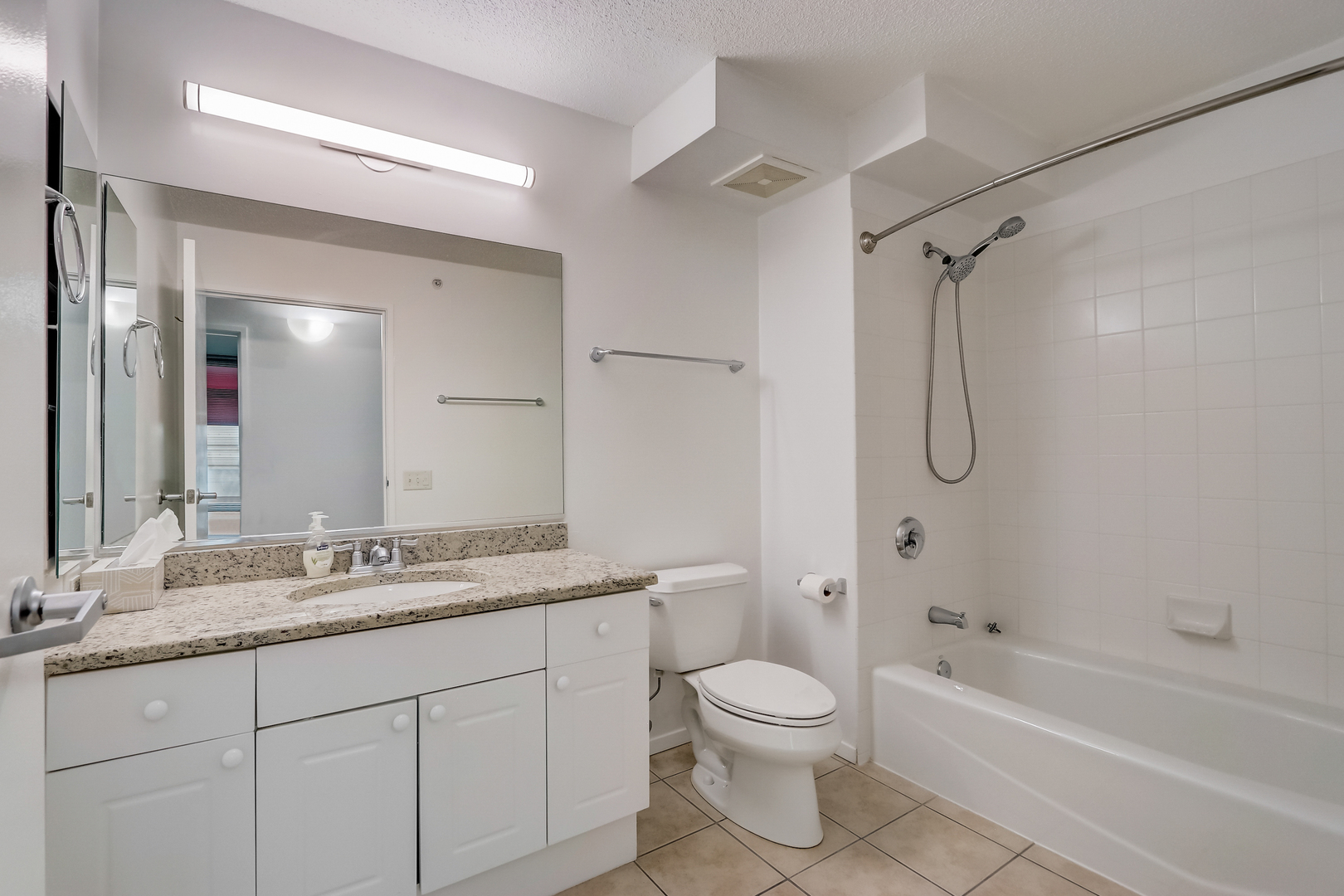 800 Elgin Road, Unit 1220 Evanston, IL 60201 - Photo 19 of 39 a bathroom with a granite countertop sink a toilet and a bathtub