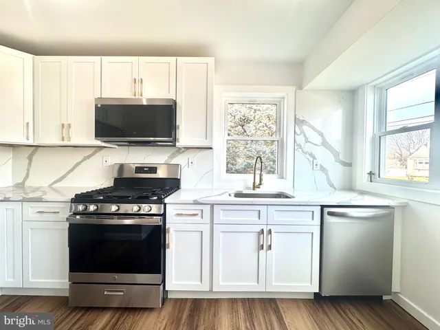 a kitchen with white cabinets and appliances