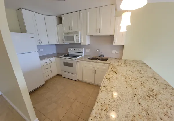 a kitchen with white cabinets a sink stove and refrigerator