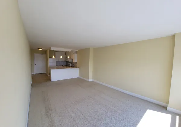 a view of an empty room and a kitchen