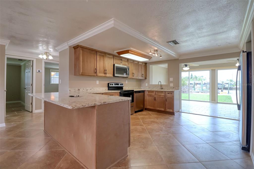 13637 Lagoon Drive Hudson, FL 34667 - Photo 13 of 36 a large kitchen with kitchen island a sink a counter top space a stove and cabinets