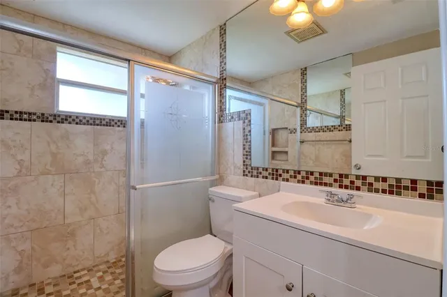 a bathroom with a granite countertop sink mirror vanity and toilet