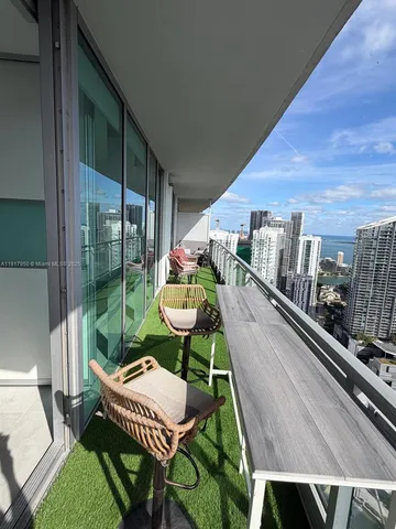 a balcony with a potted plant and outdoor seating
