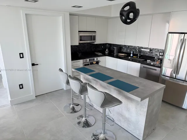 a kitchen with stainless steel appliances granite countertop a sink a stove a refrigerator a washer and dryer