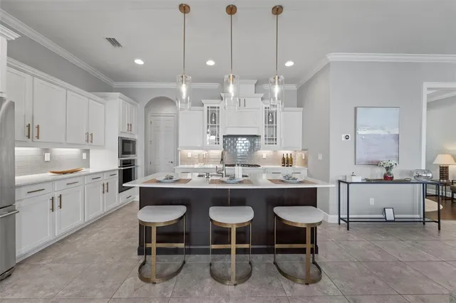 a kitchen with stainless steel appliances granite countertop a sink a stove a refrigerator and white cabinets with wooden floor