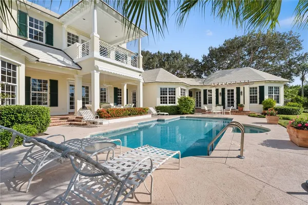 a view of a white house with a swimming pool and a chairs