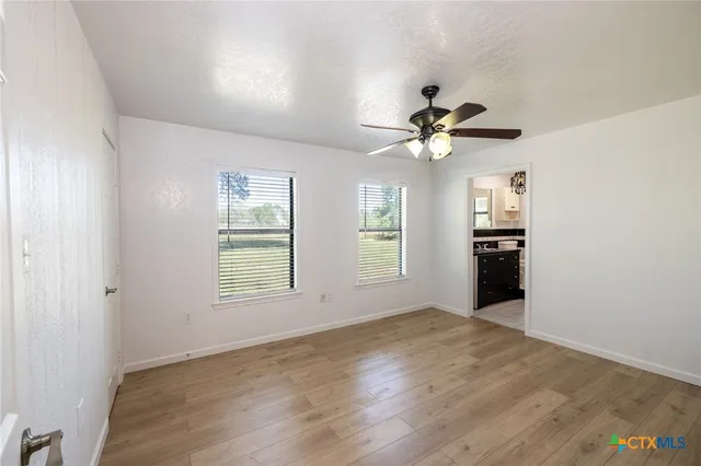 a view of an empty room with a window and a kitchen