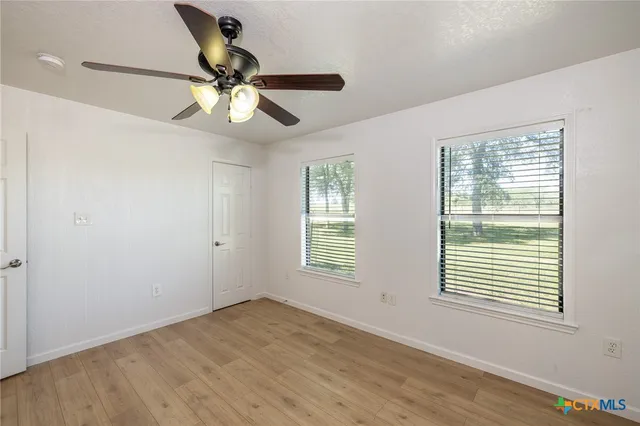 a view of empty room with wooden floor and fan