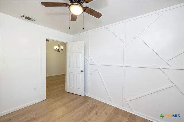 an empty room with wooden floor fan and windows