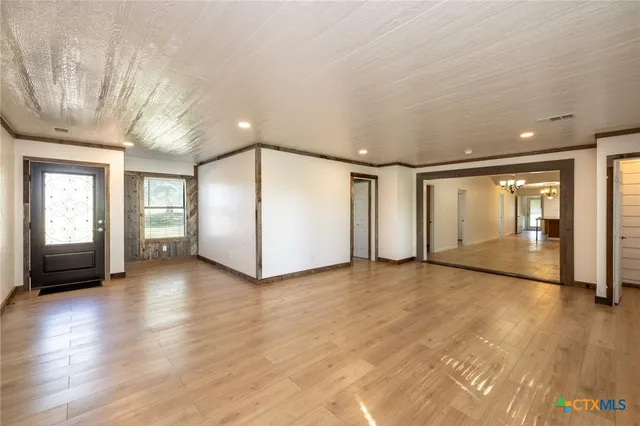 a view of an empty room with window and wooden floor