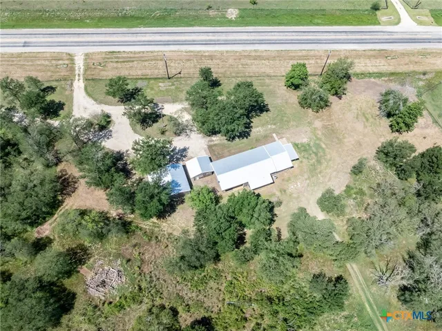an aerial view of a house with a yard and large trees all around