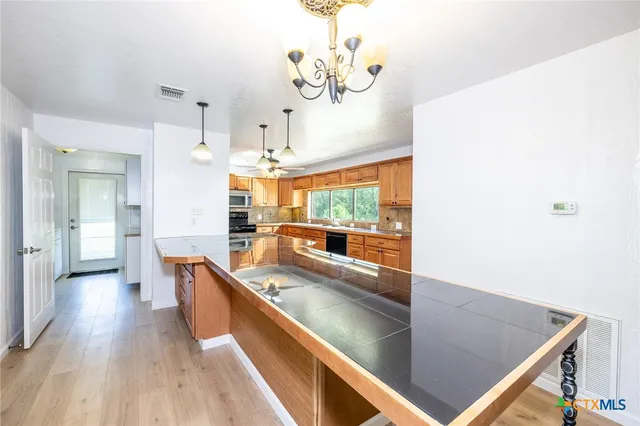 a kitchen with stainless steel appliances granite countertop a sink a stove and a wooden floors