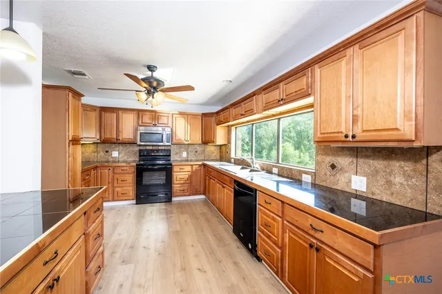 a kitchen with stainless steel appliances kitchen island granite countertop a stove a sink and a refrigerator