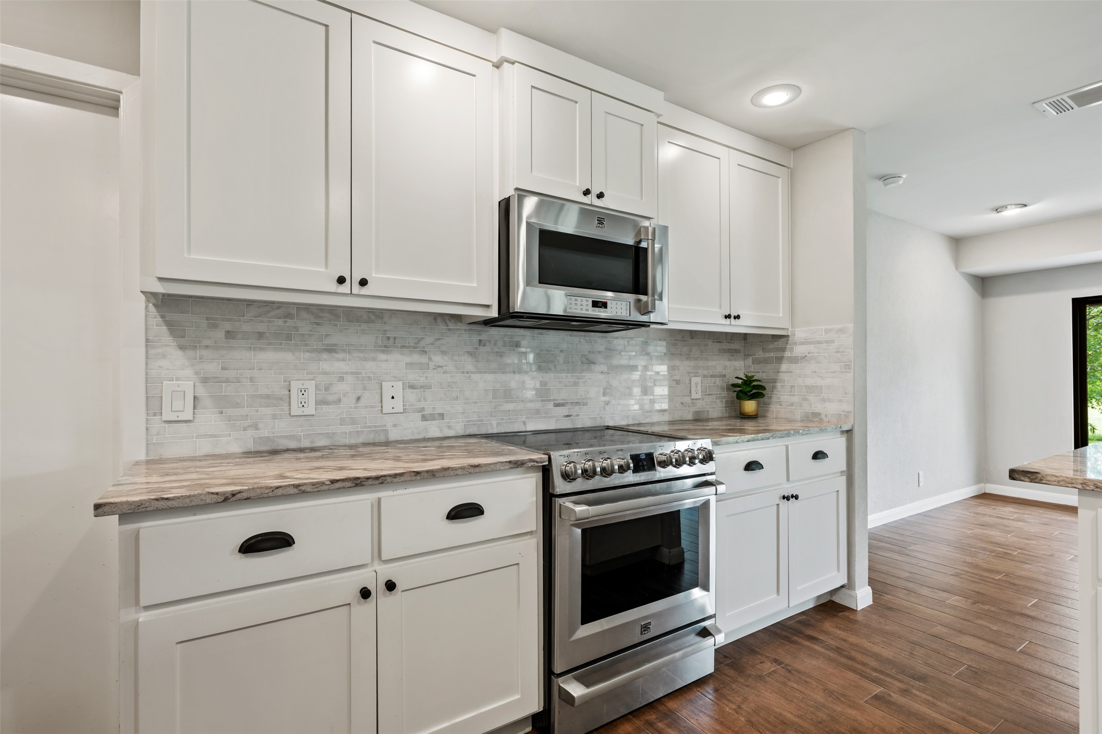 1600 Pin Oak Lane Round Rock, TX 78681 - Photo 21 of 40 Modern kitchen featuring white shaker cabinetry, stainless steel appliances, a tile backsplash, and stone countertops