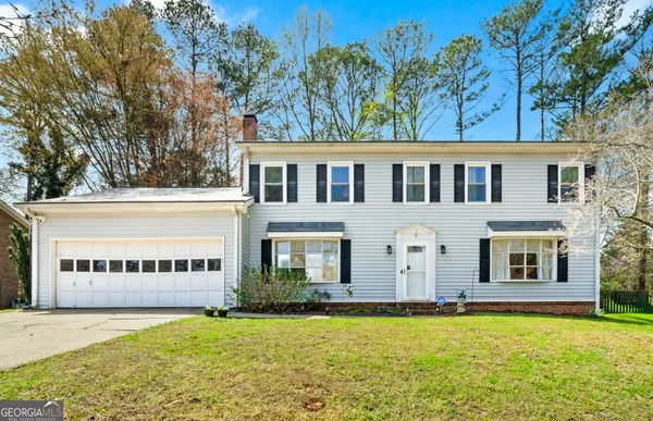 a view of a house with a yard and large tree