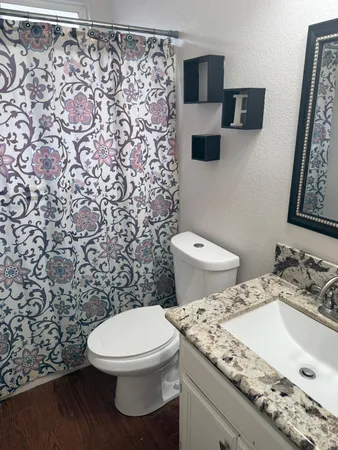 a bathroom with a granite countertop toilet and a sink