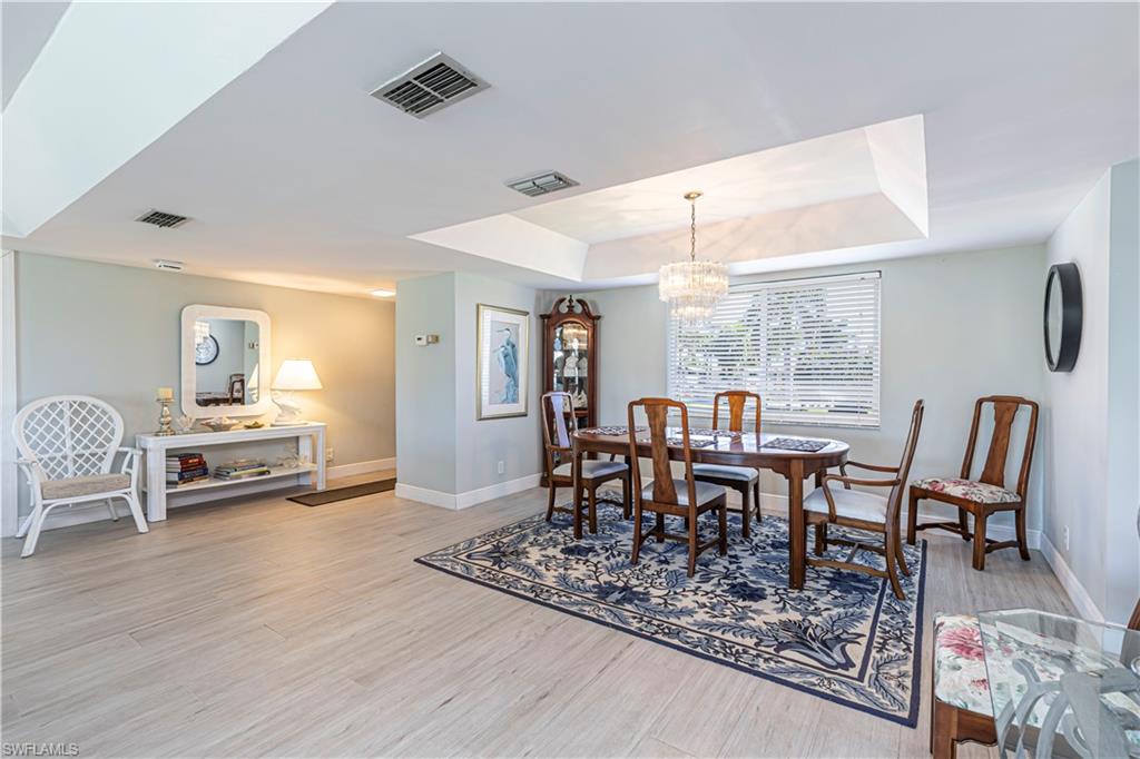 230 Albi Road, Unit 2494 Naples, FL 34112 - Photo 8 of 22 Dining area with a tray ceiling, a chandelier, and light wood-style flooring