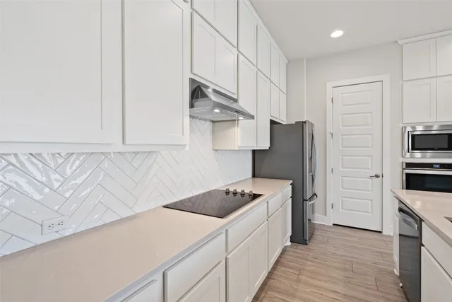 an empty room with wooden floor a ceiling fan and windows