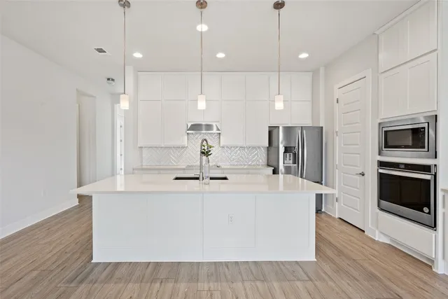 a kitchen with a sink a counter top space stainless steel appliances and cabinets