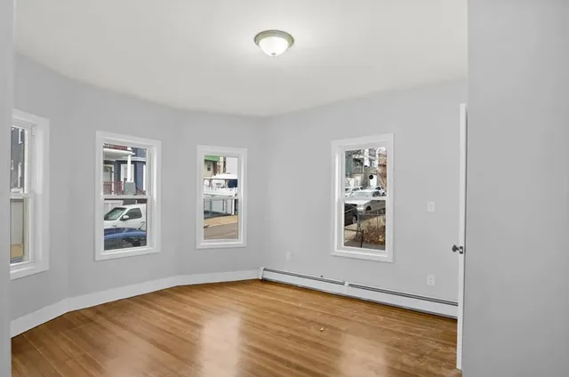 a view of an empty room with window and wooden floor