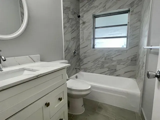 a bathroom with a granite countertop toilet a sink and bathtub