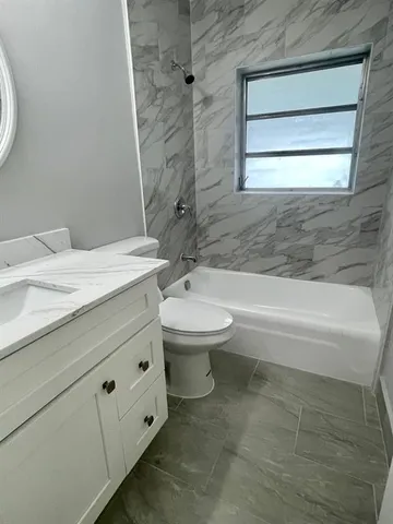 a bathroom with a granite countertop toilet a sink and a bathtub
