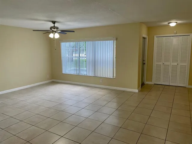 an empty room with chandelier fan and windows