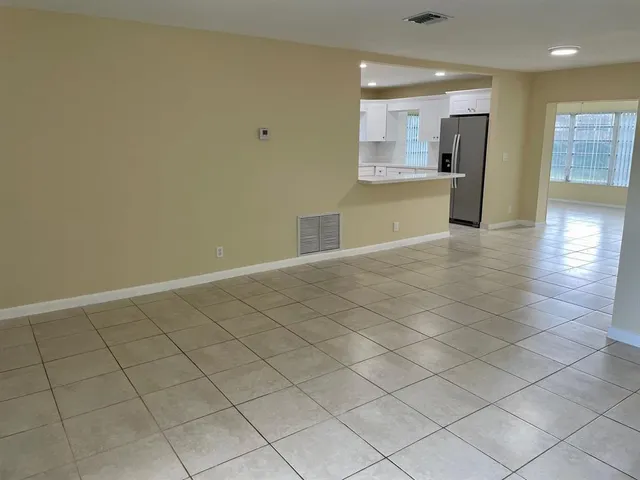 an empty room with a kitchen and natural light