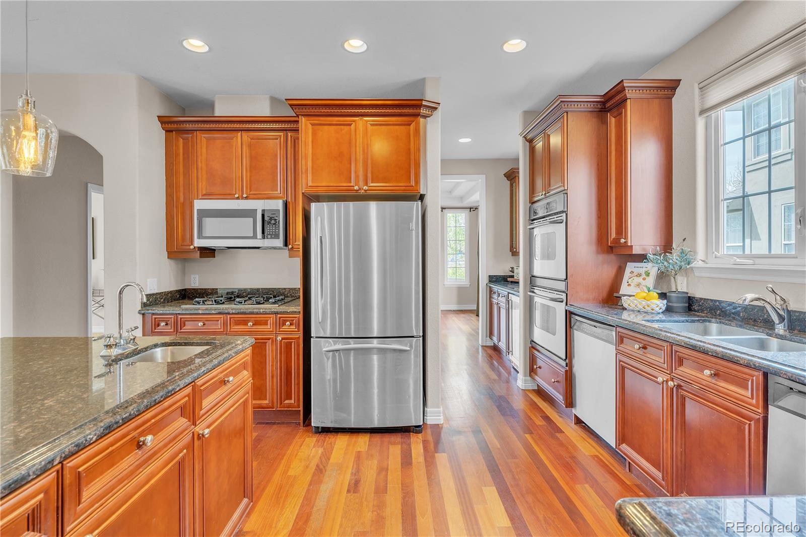 8053 East Maple Avenue Denver, CO 80230 - Photo 14 of 49 a kitchen with stainless steel appliances granite countertop a refrigerator a sink dishwasher a stove with wooden cabinets and floor