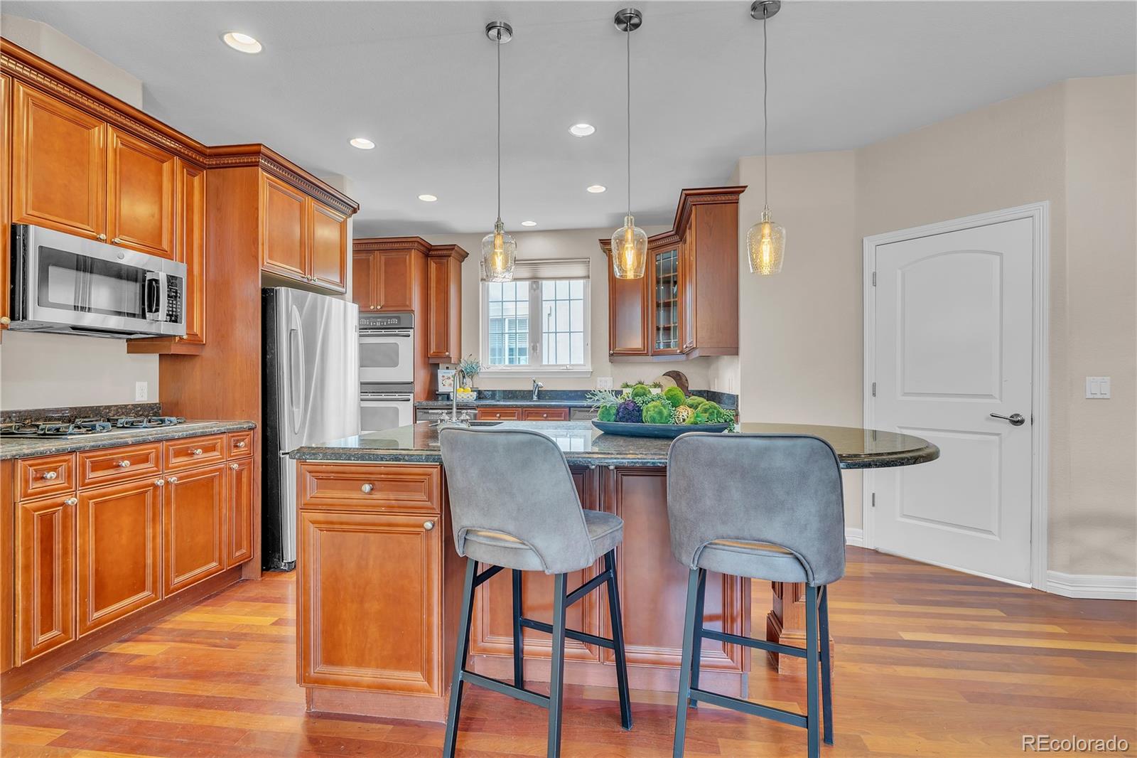 8053 East Maple Avenue Denver, CO 80230 - Photo 16 of 49 a kitchen with stainless steel appliances granite countertop a kitchen island hardwood floor sink and stove