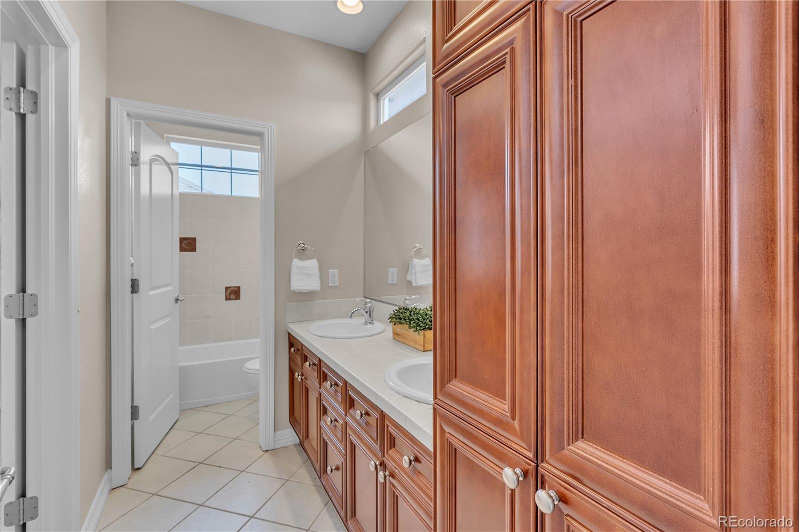 8053 East Maple Avenue Denver, CO 80230 - Photo 27 of 49 a bathroom with a double vanity sink a mirror and a bathtub