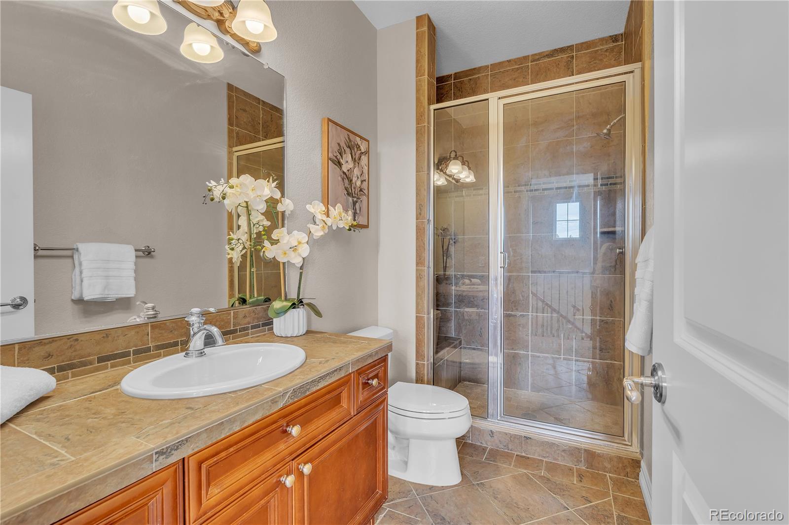 8053 East Maple Avenue Denver, CO 80230 - Photo 32 of 49 a bathroom with a granite countertop sink toilet and shower