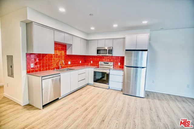 a kitchen with stainless steel appliances granite countertop a refrigerator a stove and a wooden floors