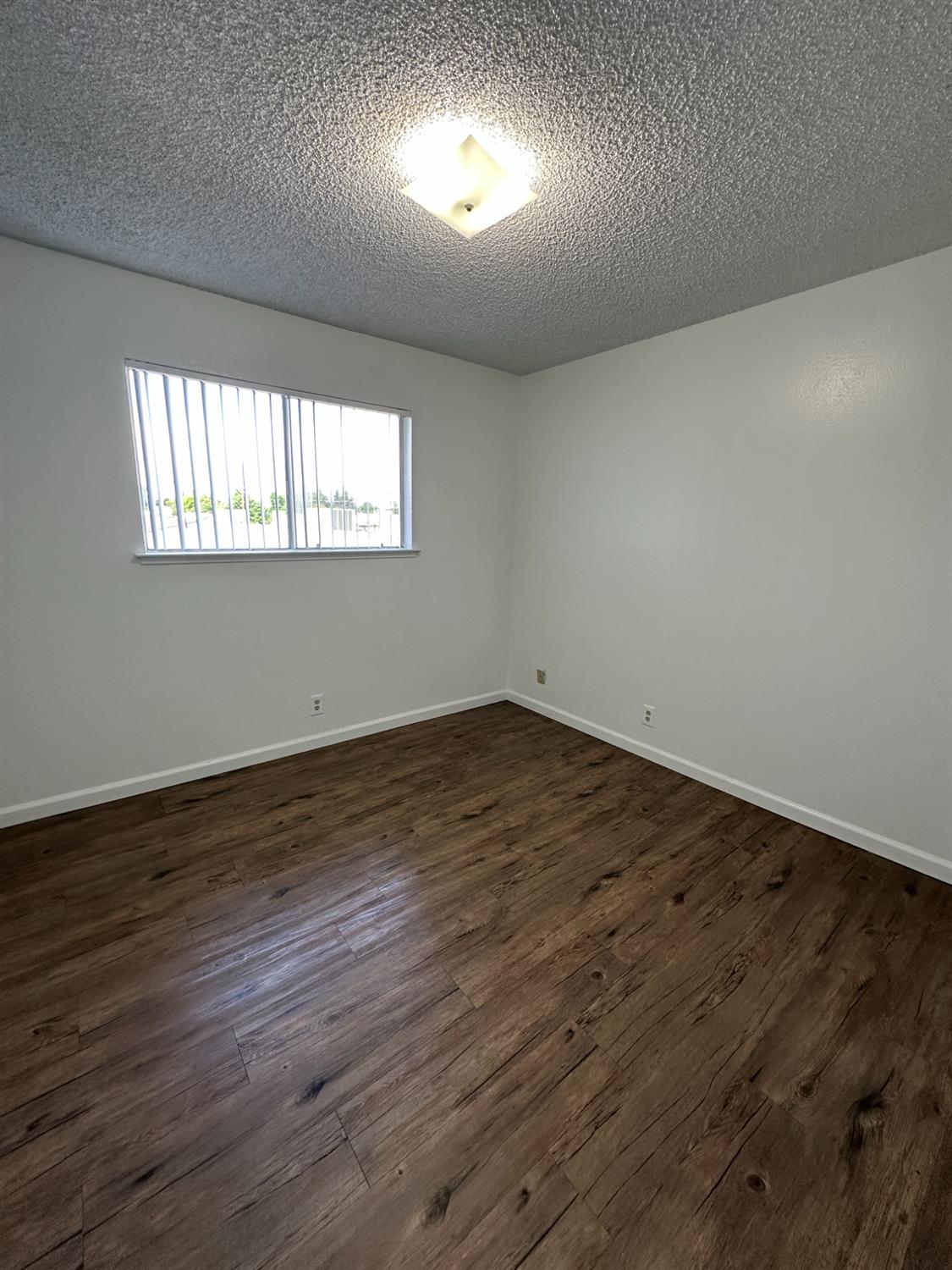 1069 Cherry Lane, Unit D Clovis, CA 93612 - Photo 12 of 18 an empty room with wooden floor and windows