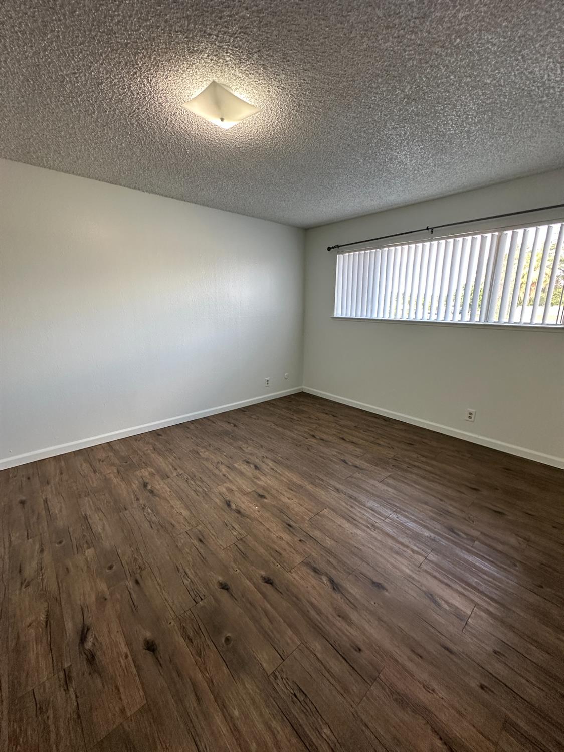 1069 Cherry Lane, Unit D Clovis, CA 93612 - Photo 14 of 18 an empty room with wooden floor and windows