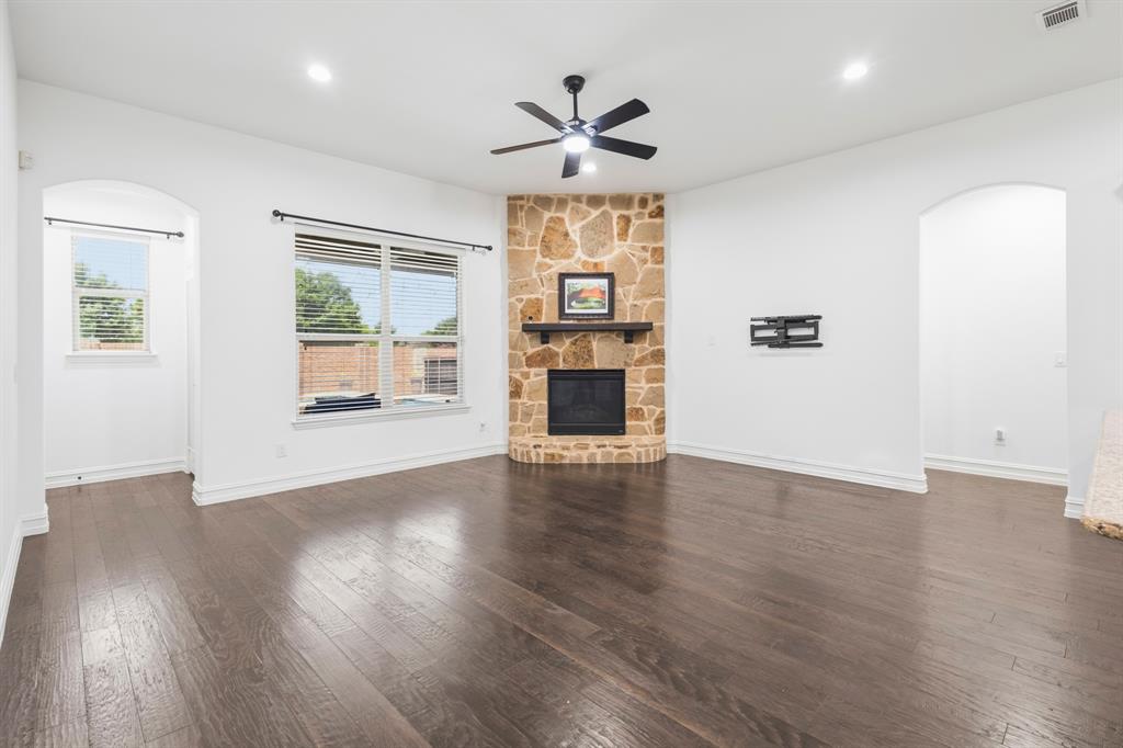 1995 Verde Court Allen, TX 75013 - Photo 16 of 30 Living area featuring a stone-clad fireplace with a wood mantel, dark wood-finish flooring, recessed lighting, and a ceiling fan