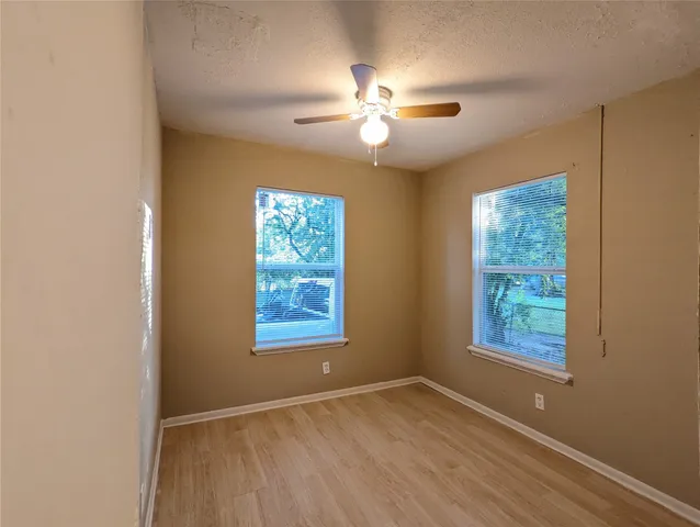 a view of an empty room with window and wooden floor