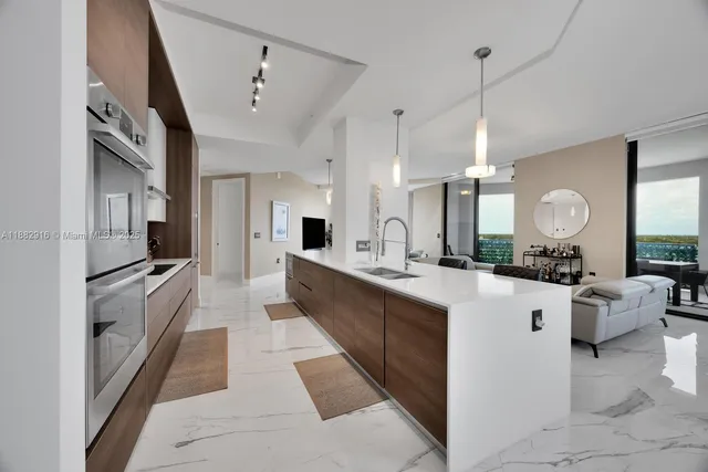 a large white kitchen with living room a stove and a chandelier