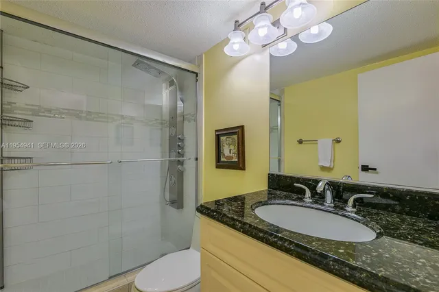 a bathroom with a granite countertop sink a toilet and a mirror