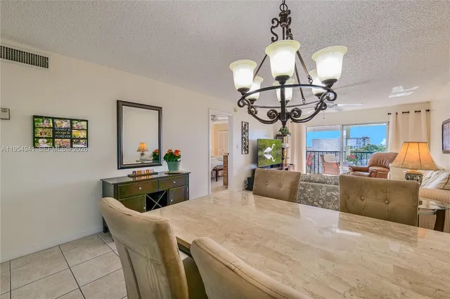 a kitchen with stainless steel appliances kitchen island granite countertop a table and a chandelier