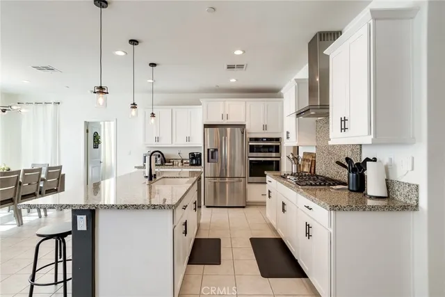 a kitchen with stainless steel appliances granite countertop a stove top oven a refrigerator a sink and dishwasher with white cabinets