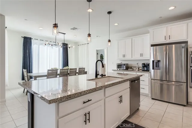 a kitchen with granite countertop a refrigerator a sink and cabinets