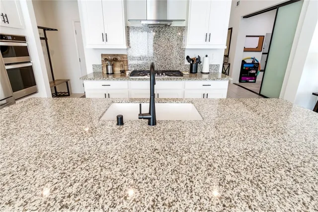 a kitchen with stainless steel appliances kitchen island granite countertop a refrigerator and a sink