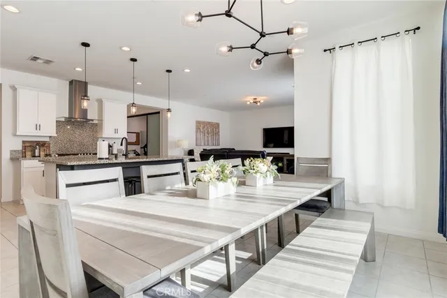 a kitchen with stainless steel appliances kitchen island granite countertop a table chairs and a refrigerator