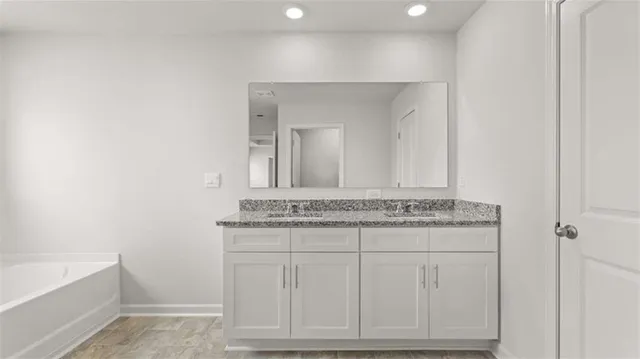 a bathroom with a granite countertop sink a toilet a mirror and bathtub