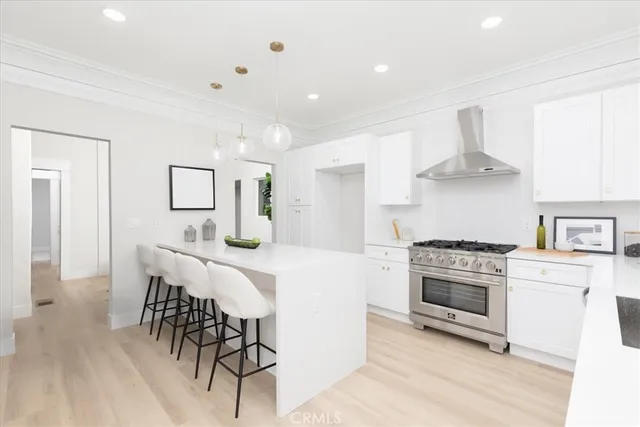 a kitchen with stainless steel appliances a stove a sink dishwasher a refrigerator white cabinets and wooden floor next to a window