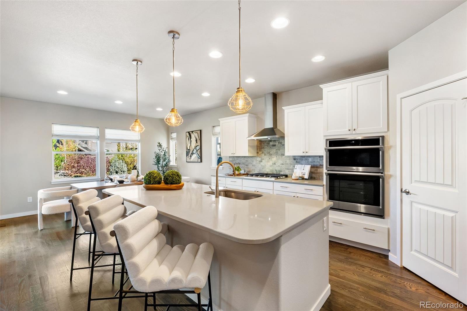 4508 Captain Jack Lane Colorado Springs, CO 80924 - Photo 12 of 50 a kitchen with stainless steel appliances granite countertop a stove top oven a sink a dining table and chairs with wooden floor