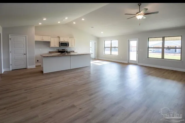 a large kitchen with stainless steel appliances granite countertop a large counter top a sink and a refrigerator