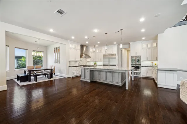a kitchen with a stove a sink a refrigerator and white cabinets with wooden floor